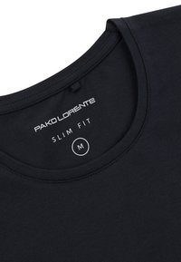 Czarny, dopasowany t-shirt z miękkiej bawełny. Charakteryzuje się okrągłym dekoltem, widocznym ściegiem oraz metką z rozmiarem 'M' wszytą wewnątrz kołnierza.