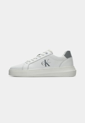 Bijele kožne tenisice s teksturiranim gumenim potplatom, ukrašene srebrnim detaljima i s logotipom "calvinKlein" s strane u sivoj boji.