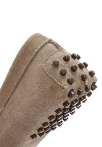 Scarpa in camoscio beige con forma arrotondata, caratterizzata da accenti scuri a borchie e una finitura texturizzata. Il design presenta dettagli di cucitura ordinati.