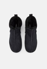 Sorte suede ankelboots med bløtt pelstoplining, med glidelås og flat såle. Enkelt design med minimale hardwaredetaljer.