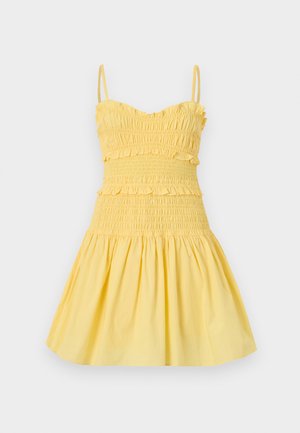 Robe jaune sans manches avec fines bretelles, corsage froncé, accents à volants et jupe évasée.