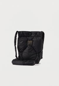 Černá prošívaná látková taška obdélníkového tvaru, s dlouhým popruhem, knoflíkovým uzávěrem a štítkem vpředu. Měkká textura.