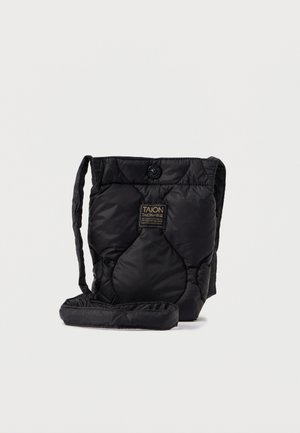 Geantă din material quilted negru, cu o formă rectangulară, având un breloc lung, închidere cu nasture și un eticheta pe față. Textură moale.