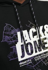 Sudadera negra con un diseño gráfico en blanco y púrpura de mapas urbanos. Cuerdas gruesas negras con acentos blancos. Texto en negrita "JACK & JONES".