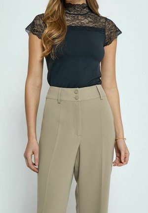 Czarny top z koronkowym zdobieniem przy dekolcie i krótkimi rękawami, w połączeniu z jasnobeżowymi, wysoko taliowanymi spodniami z dwoma guzikami jako akcentami.