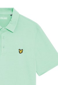 Licht mintgroene polo met een gladde stof. Voorzien van een drieknoopsluiting en een zwart-gele geborduurde logo op de borst.
