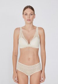 Bralette de encaje y braguitas altas a juego en color crema, con bordes festoneados y patrón de encaje floral. Textura suave y diseño de escote en V.