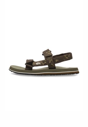 Sandales de camouflage marron avec des sangles ajustables et une semelle en caoutchouc verte. Comprend un semelle intérieure texturée et une ligne d'accent blanche sur la semelle.