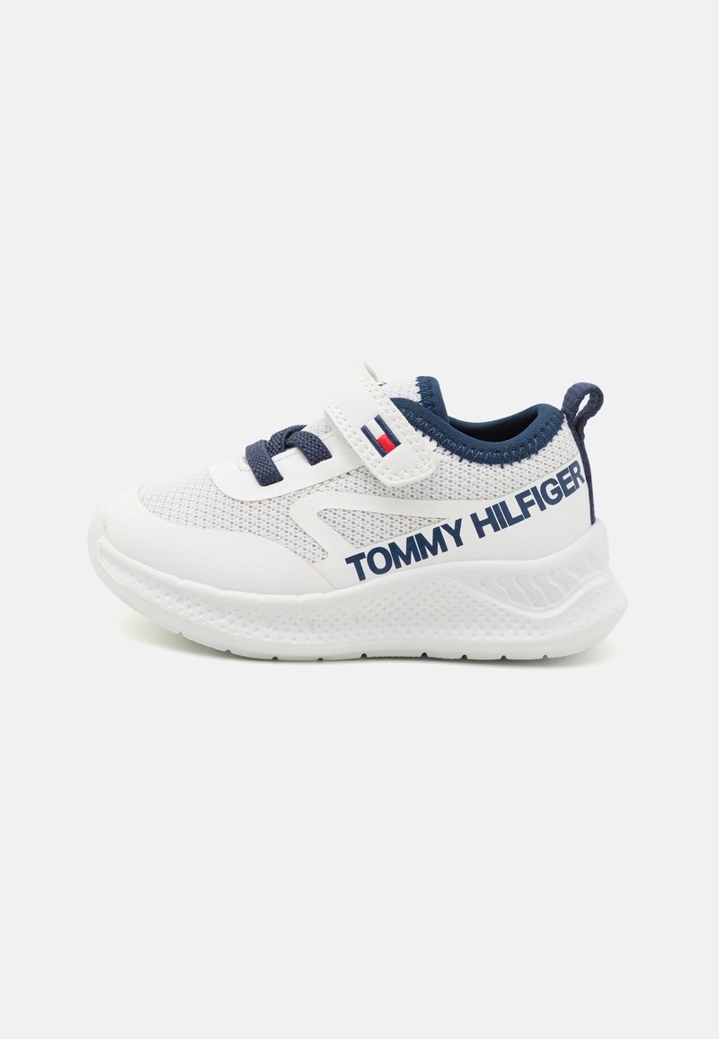 Baskets blanches avec une tige en mesh et des accents marine. Comprend une sangle en velcro, une semelle texturée et le logo "TOMMY HILFIGER" en marine.