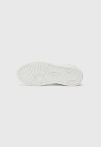 Suola di sneaker bianca con un motivo testurizzato, logo rotondo, forma piatta e finitura liscia, progettata per garantire aderenza e comfort.