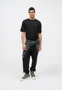 Μαύρο κοντομάνικο μπλουζάκι, χαλαρό μαύρο παντελόνι και γκρι φούτερ tied γύρω από τη μέση. Γκρι ψηλές αθλητικές χνουδωτές με κόκκινες λεπτομέρειες.