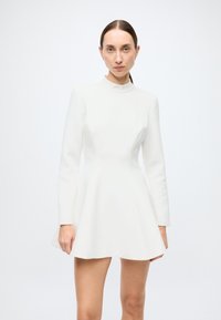White long-sleeve dress with a fitted bodice, flared skirt, and high neckline, made of smooth fabric. Simple design with no visible patterns.