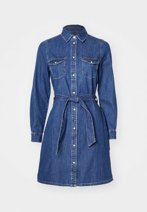 Džinsinė suknelė su ilgomis rankovėmis, mygtukų priekyje, krūtinės kišenėmis ir rišamu juosmeniu. Yra klasikinis apykaklė ir vidutinio ilgio sijonas.