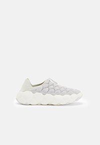 Ljust grå stickad sneakers med strukturerat bubbelmönster och tjock vit vadderad sula, slip-on stil med dragflik på en enfärgad bakgrund.