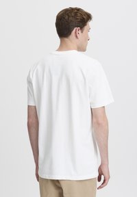 Hvit bomulls T-skjorte med kort erm, rund hals og et enkelt design. Glatt tekstur, uten synlige mønstre eller detaljer.