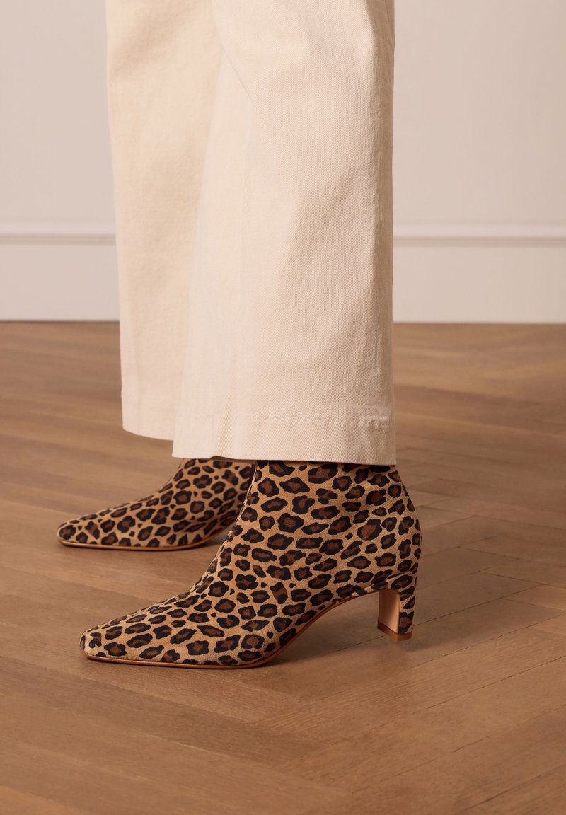 Leopardenmuster Ankle Boots aus Wildleder, mit spitzem Zeh und mittelhohem Absatz. Gestylt mit hellen, weiten Hosen.