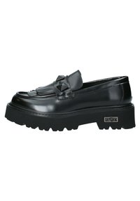 Mocasines de charol negro con una suela gruesa y texturizada, que presentan un fleco decorativo y acentos en forma de pirámide en la parte superior.