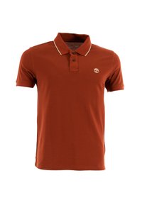 Polo shirt color ruggine con colletto classico, chiusura a due bottoni e dettagli a strisce beige. Presenta un piccolo logo sul petto.