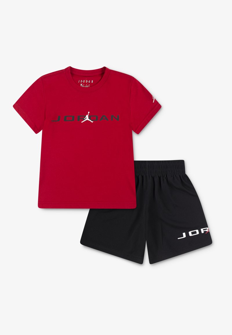 Punainen puuvillapitkähiha T-paita, jossa on musta "JORDAN"-logo ja valkoinen Jumpman-silhuetti. Mustat sortsit, joissa on valkoinen "JORDAN"-logo. Rentouttava urheiluasu.