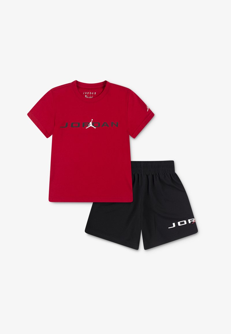 Rde bombažna majica s kratkimi rokavi z črnim logotipom "JORDAN" in belim silhuetom Jumpman. Črne kratke hlače vsebujejo bel logotip "JORDAN". Priložnostna športna oblačila.