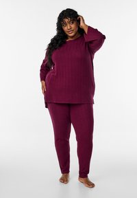 Ensemble de vêtements d'intérieur côtelé bourgogne comprenant un haut à manches longues ample et un pantalon fuselé, confectionné en tissu doux au toucher lisse.