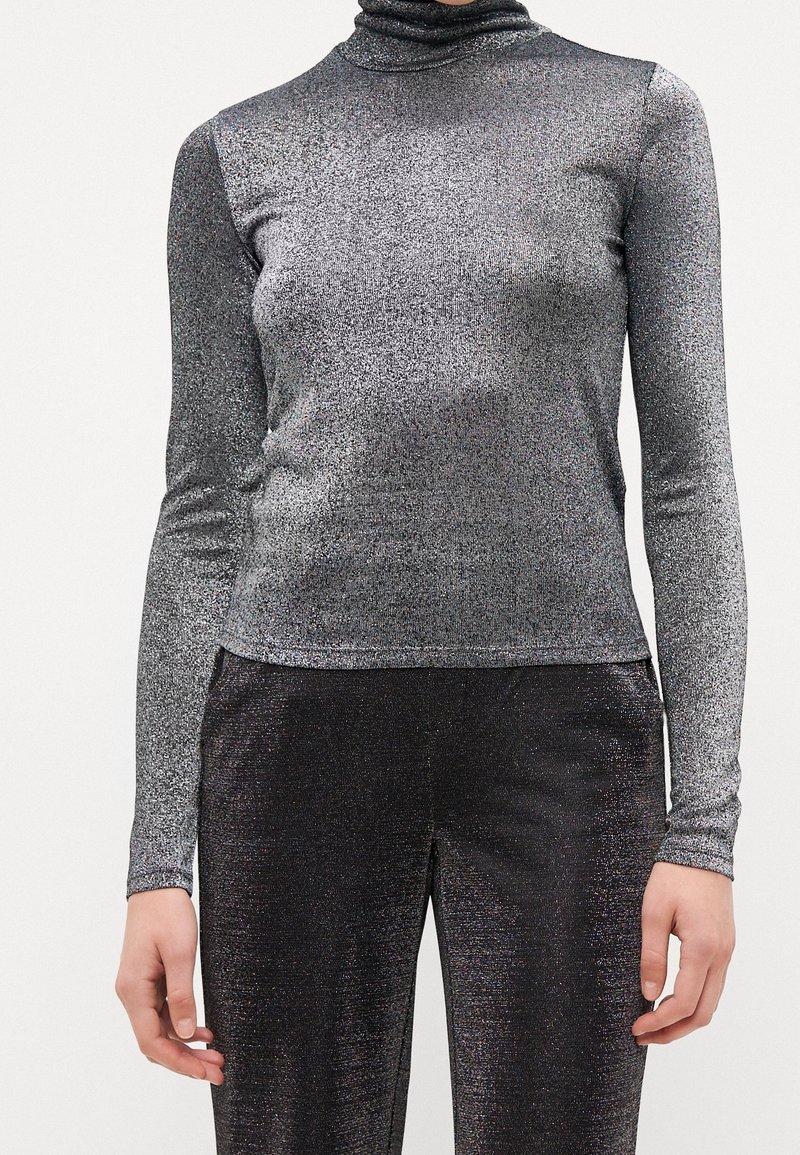 Silberner metallischer Langarm-Turtleneck-Oberteil mit enganliegendem Design und schimmernder Textur. Glattes Material mit einem dezenten Glanz auf der Oberfläche.