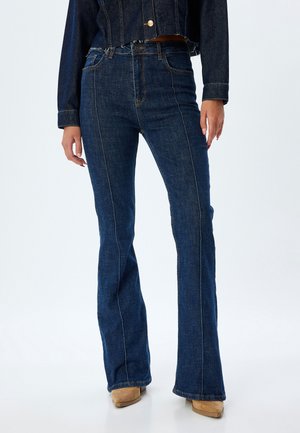 Jeans en denim bleu marine évasés avec taille haute, dotés de coutures contrastantes et d'un design classique à cinq poches. Texture lisse, coupe structurée.