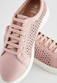 Lys rosa lædersneakers med vævet tekstur på siderne, flade snørebånd og hvide gummisåler. Udsmykket med en polstret krave.