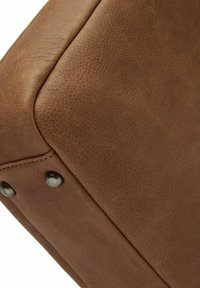 Bruin lederen kussen met een gladde textuur, voorzien van zichtbare stiksels, afgeronde randen en zwarte metalen accentknopen.