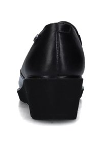 Mocassino in pelle nera con tacco spesso, visto da dietro su sfondo bianco.