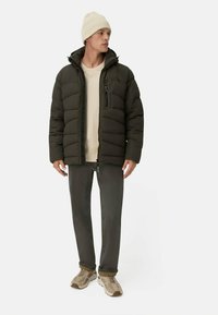 Sort dunjakke med vandret syninger, lynlås lommer og hætte. Sammen med en beige skjorte, mørkegrå bukser og beige sneakers.