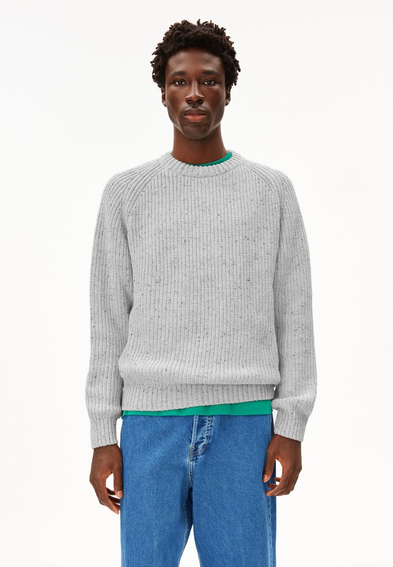Hellgrauer gestrickter Pullover mit Rippenstruktur, runder Halslinie und langen Ärmel. Trägt man über einem grünen Hemd, kombiniert mit blauen Jeans.