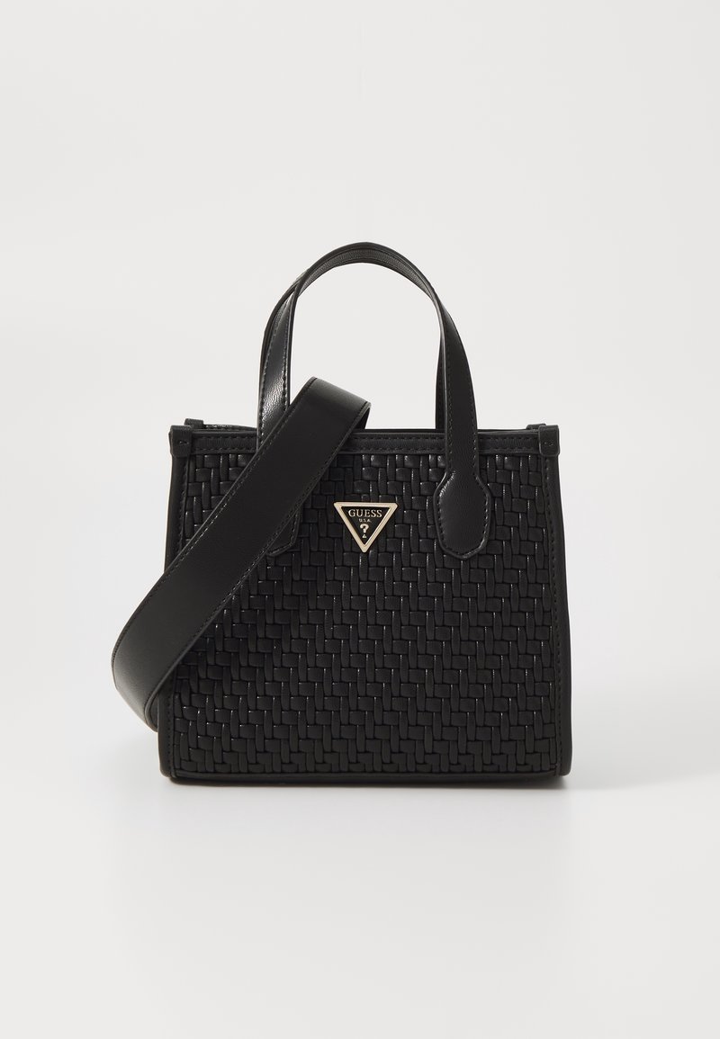 Sac à main en cuir noir tressé avec double poignées, bandoulière longue amovible, et petit logo Guess métallique triangulaire sur le devant.