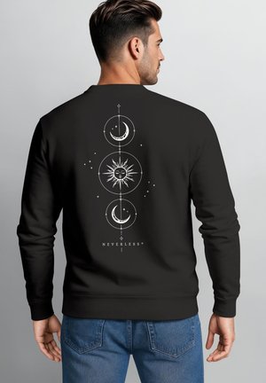 Mann trägt schwarzen Pullover mit weißem Sonne- und Mond-Himmelsdesign und dem Wort "NEVERLESS" auf dem Rücken, vom Kamera weggewandt.