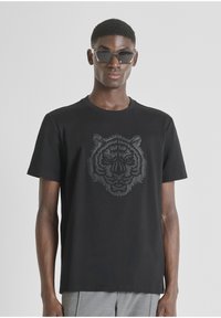 Crna pamučna majica s trodimenzionalnim grafičkim prikazom tigrove glave u tamno sivoj boji sprijeda. Kratki rukavi i okrugli izrez.