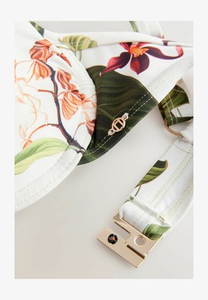 Soutien-gorge en tissu blanc avec un imprime floral en orange et violet. Bretelle réglable avec un détail de fermoir en or et des accents verts.