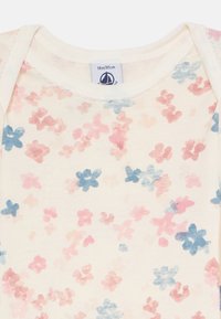 Helles Baby-Body in Cremefarbe mit floralen Mustern in Pink, Rot und Blau sowie einem Etikett, das die Größe 18m/81cm anzeigt.