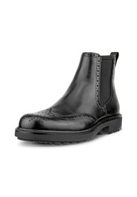 Black leather Chelsea boots feature a brogue design with perforations, elastic side panels, and a thick rubber sole.