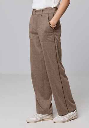 Pantalons marron texturés avec deux poches avant, une fermeture à un bouton et une coupe droite. Associés à des baskets blanches.