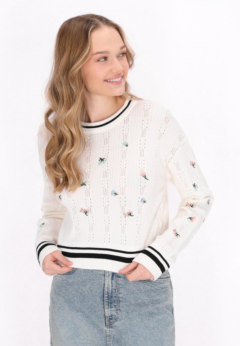 Pulover alb tricotat cu broderie florală, manșete și tiv în dungi negre și albe, având un design texturat și cu țesătură deschisă.