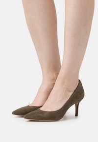 Olivgrön mocka högklackade skor med spetsig tå och smal klack, med en slät yta och en lågskuren design längs sidorna.