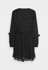 Schwarzes Kleid aus durchscheinendem Stoff mit einem silbernen Punktemuster. Es hat lange Ärmel, einen gerafften Saum und einen runden Ausschnitt. Fließendes Design mit Falten.