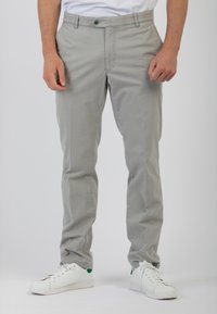 Pantaloni in cotone grigio chiaro con un design a gamba dritta, dotati di chiusura frontale con bottone e tasche laterali, abbinati a sneakers bianche.