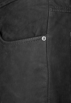 Zwarte leren broeken met een zijzak met een zilveren drukknoopsluiting en zichtbare stikdetails langs de naden. Gladde textuur.