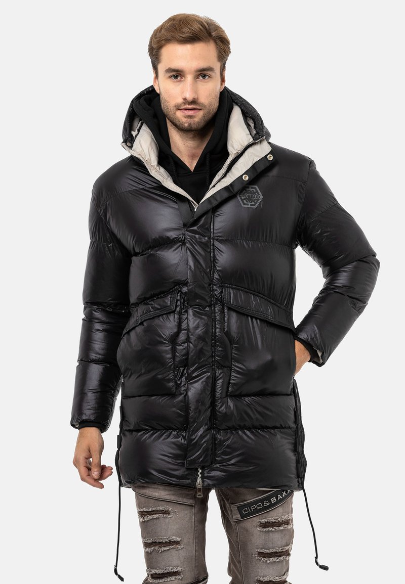 Schwarze Steppjacke mit Kapuze, ausgestattet mit einem hellgrauen Innenfutter, einem Reißverschluss vorne, verstellbaren Kordelzügen und einem Logo-Detail auf der Brust.