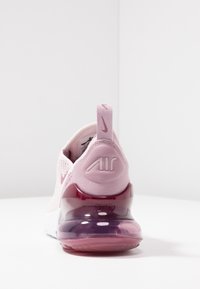 Tenisky Nike Air v světle růžové síťovině s polstrovanou průhlednou podrážkou. Obsahují poutko na patě s logem "AIR" a gradientní akcenty.