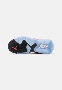 Black and blue sneaker sole with textured rubber design, featuring a red Jumpman logo and white Nike branding. Smooth, translucent sections.