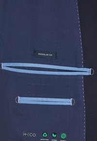 Marineblaue Regular Fit Jacke mit hellblauen Akzenten, ausgestattet mit zwei horizontalen Taschen und Anhängern, die nachhaltige Materialien und umweltfreundliche Produktion kennzeichnen.