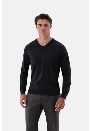 Dunkelgrauer V-Ausschnitt-Pullover aus weichem Material, mit langen Ärmeln, figurbetontem Schnitt und glatter Textur, kombiniert mit grauen Hosen.