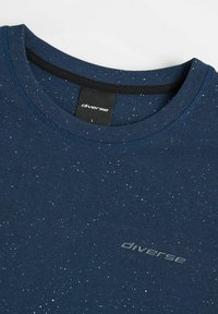 Granatowy, kropkowany T-shirt z dekoltem typu crew neck, z logo "diverse" na piersi oraz czarną metką wewnętrzną przy kołnierzu z rozmiarem L.